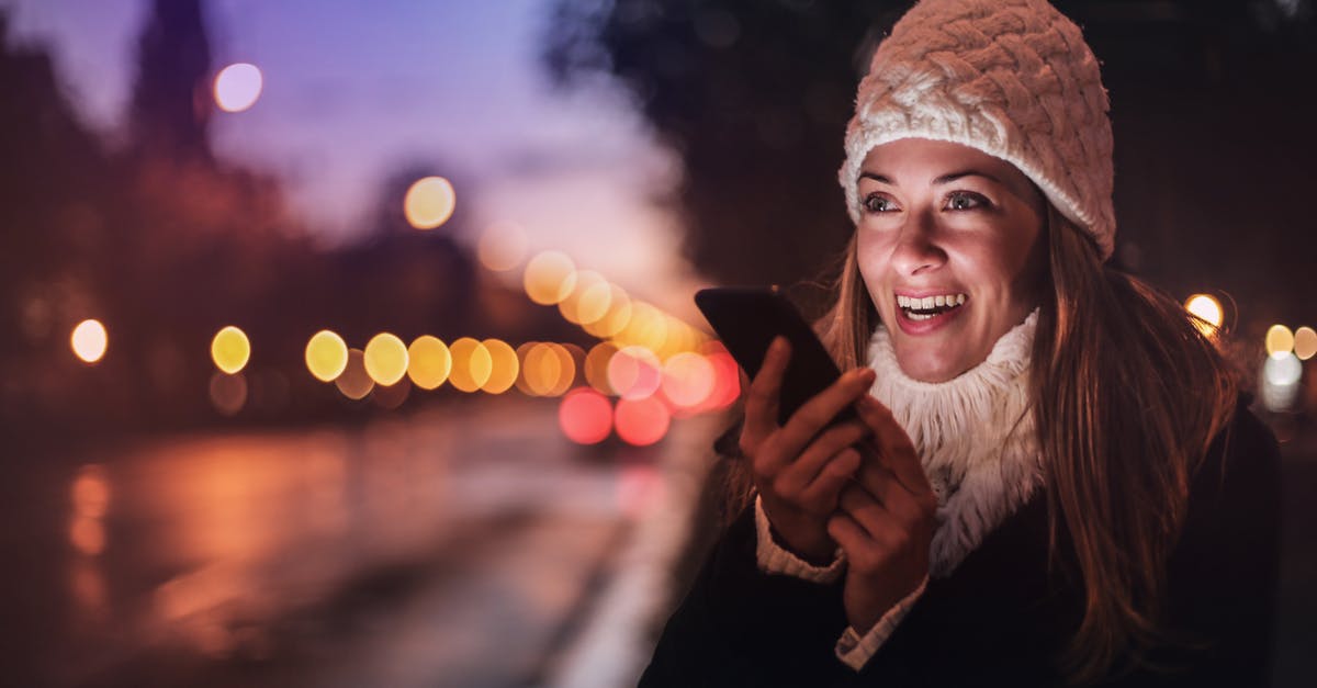 Why can't I hear voice chat in my headset? - Cheerful woman recording voice message on smartphone in street