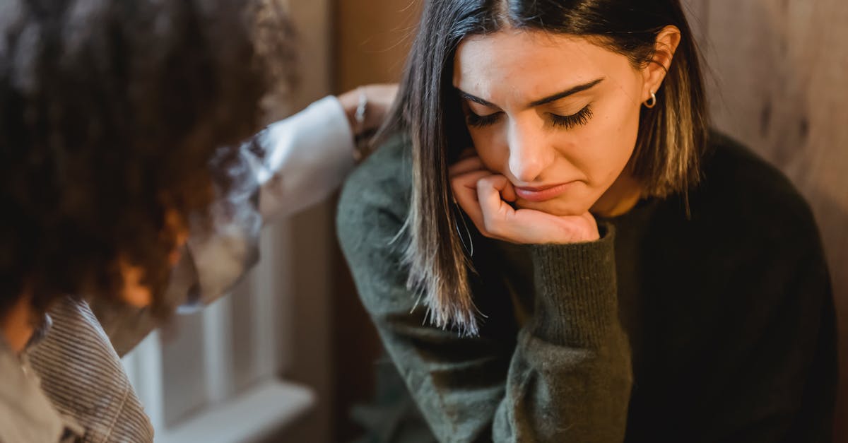 Why can't I summon my friend to help me? - Crop woman tapping shoulder and comforting upset female friend while sitting at home together