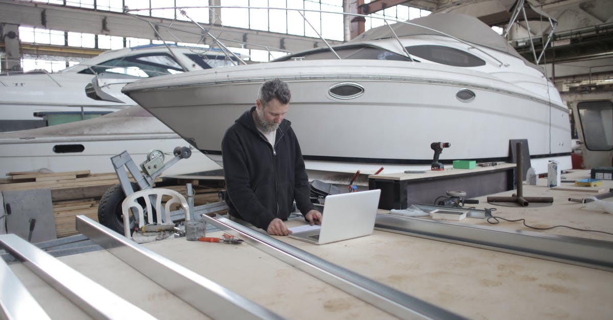 Why can't I use a Robot Workbench at Boston Airport Ruins? - Adult worker using laptop at workbench during work in boat garage Why can't I use a Robot Workbench at Boston Airport Ruins? - Adult worker using laptop at workbench during work in boat garage