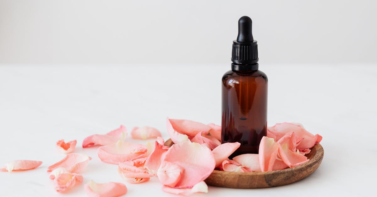 Why do I sometimes regain an estus flask charge? - Gentle pale pink wavy rose petals placed on small round wooden plate and table near dark glass essence flask on white background