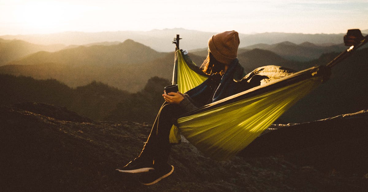 Will time distortions disappear if I rest at camp? - Unrecognizable woman sitting in hammock above mountains